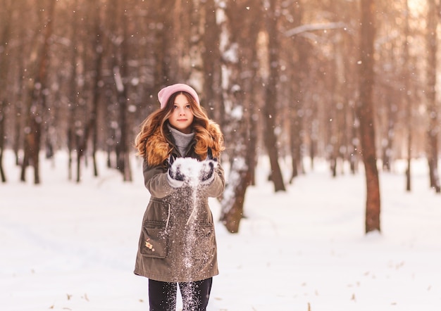 Menina brincando com neve no parque no inverno