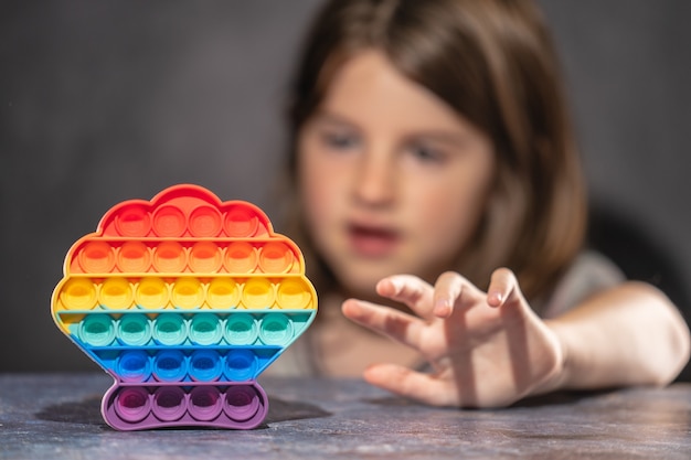 Foto menina brincando com o arco-íris colorido pop-lo anti-stress de brinquedo de silicone.