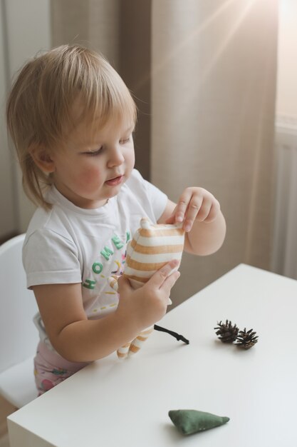 Menina brincando com o símbolo do brinquedo do tigre pequeno engraçado em um berçário ensolarado