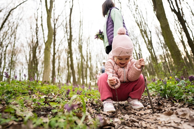 Menina brincando com paus na floresta de primavera