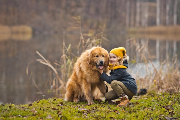 Menina brincando com um grande cão de guarda no lago de outono 9815