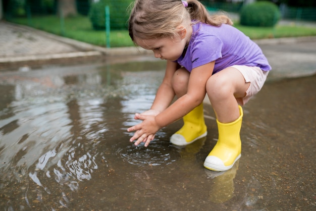 Menina brincando em uma poça depois da chuva