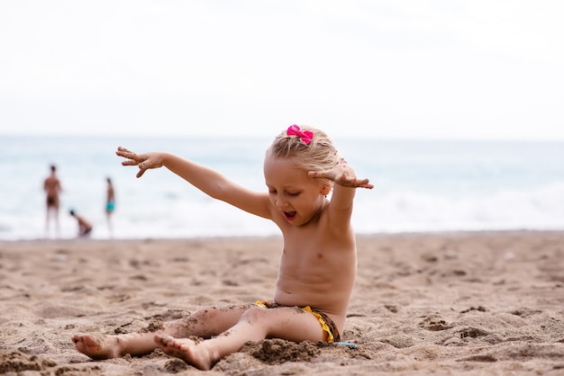 Menina brincando na areia perto do mar