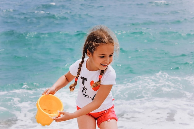 Menina brincando na praia perto do mar azul