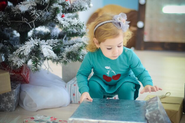 Foto menina brincando na sala com decorações de natal e presentes embrulhados