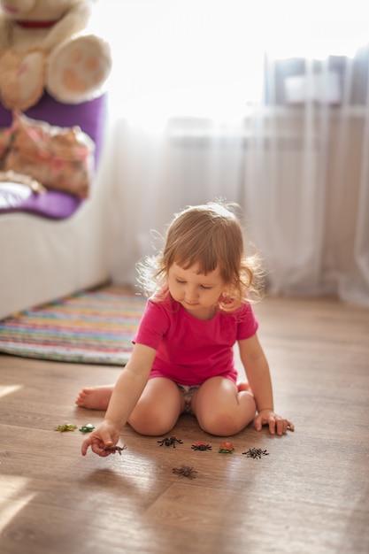 Menina brincando no chão da sala em pequenos brinquedos