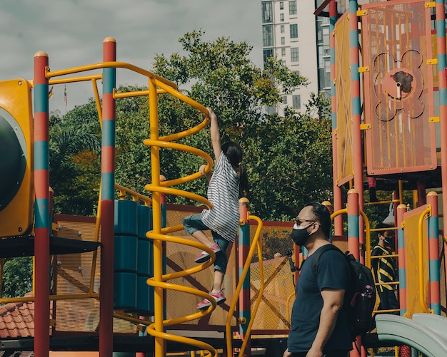 Foto menina brincando no playground com o pai