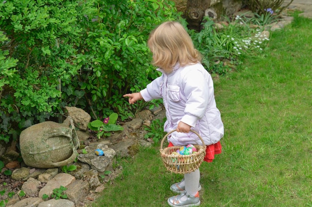 Menina caçando ovo de páscoa em um jardim de primavera no dia de páscoa