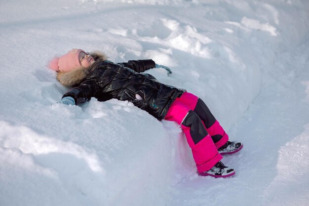 Menina caminha ao ar livre no dia de inverno nevado no parque