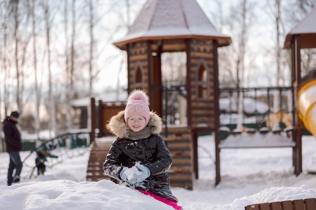 Menina caminha ao ar livre no dia de inverno nevado no parque