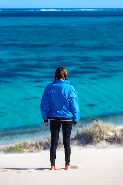 menina caminha nas dunas de areia na baía de coral com vista para o recife de ningaloo, austrália ocidental