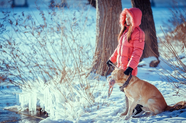 Menina caminhando com seu labrador retriever amarelo na paisagem de inverno