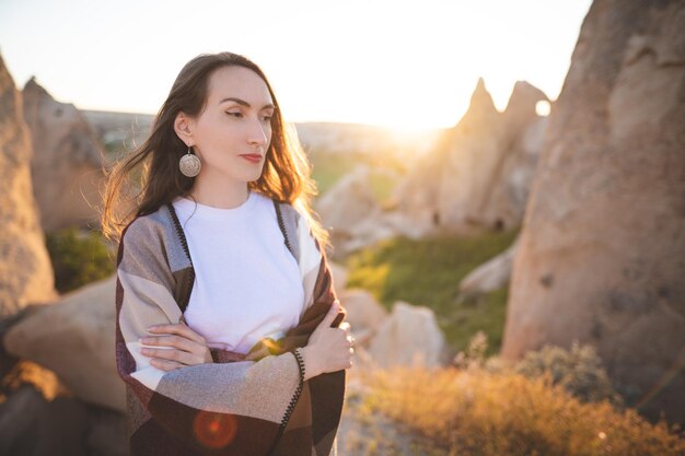 Menina caminhante de poncho no topo da montanha ao pôr do sol