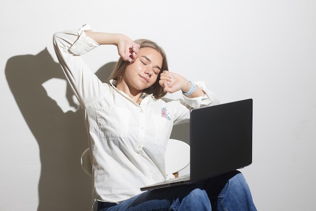 Menina cansada com laptop em fundo branco