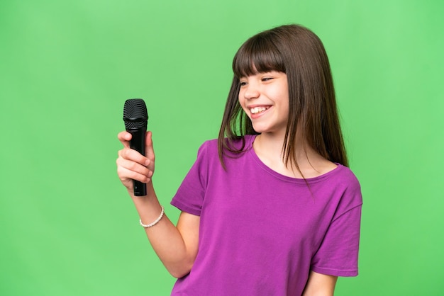 Menina cantora pegando um microfone sobre fundo isolado com expressão feliz