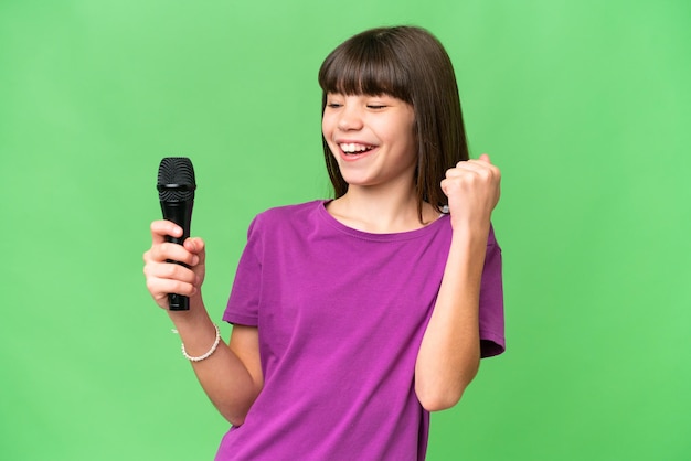Menina cantora pegando um microfone sobre fundo isolado comemorando uma vitória