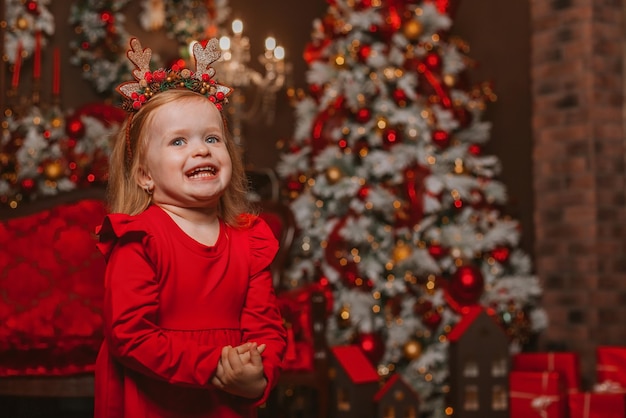 menina carismática com um vestido vermelho no fundo de decorações de Natal