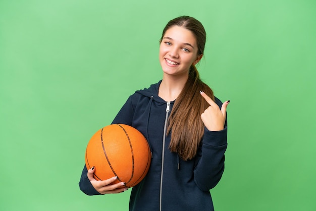 Menina caucasiana adolescente jogando basquete sobre fundo isolado, dando um polegar para cima gesto