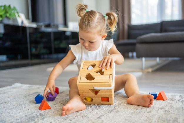 Menina caucasiana bonitinha brincando no chão em casa com brinquedos ecológicos de madeira Brinquedo Montessori A criança jogando jogos educativos