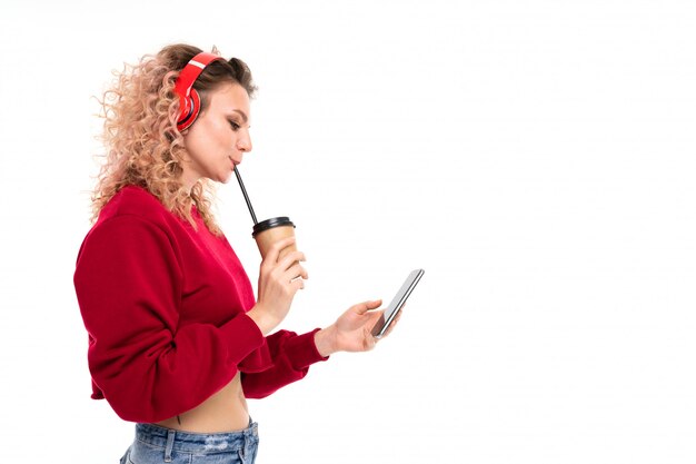 Menina caucasiana com cabelo loiro encaracolado bebe café, ouvir música e conversar com os amigos, retrato isolado