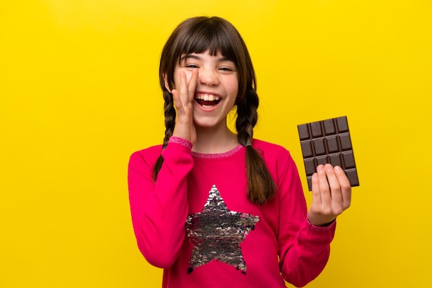 Menina caucasiana com chocolate isolado em fundo amarelo gritando com a boca aberta