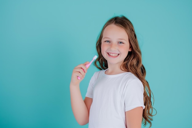 Menina caucasiana com escova de dentes na mão em fundo azul claro