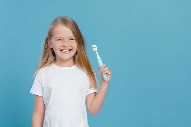Menina caucasiana com escova de dentes na mão em fundo azul claro