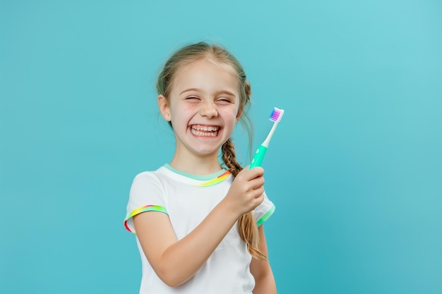 Menina caucasiana com escova de dentes na mão em fundo azul claro