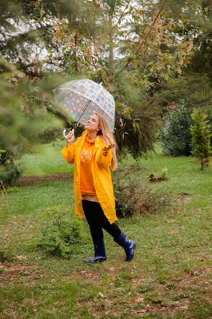 Menina caucasiana com uma capa de chuva amarela andando do lado de fora em um dia chuvoso no outono Pessoas no outono