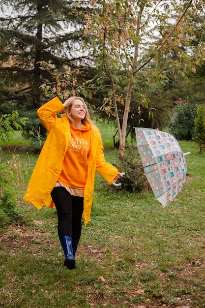 Menina caucasiana com uma capa de chuva amarela andando do lado de fora em um dia chuvoso no outono Pessoas no outono