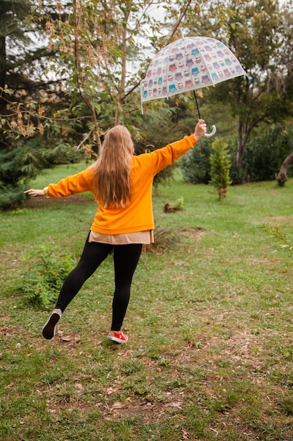 Foto menina caucasiana com uma capa de chuva amarela andando do lado de fora em um dia chuvoso no outono pessoas no outono