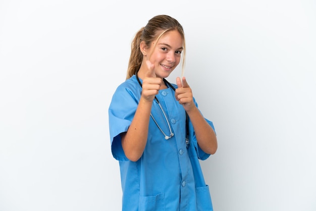 Menina caucasiana disfarçada de cirurgião isolada no fundo branco, apontando para a frente e sorrindo