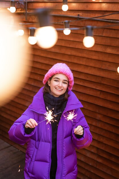 Menina caucasiana está se divertindo no inverno na rua com estrelinhas na mão, sorrindo com felicidade w ...