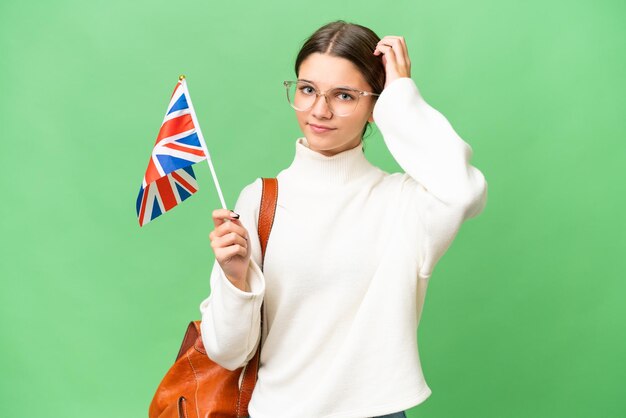 Menina caucasiana estudante adolescente segurando uma bandeira do Reino Unido sobre fundo isolado com dúvidas