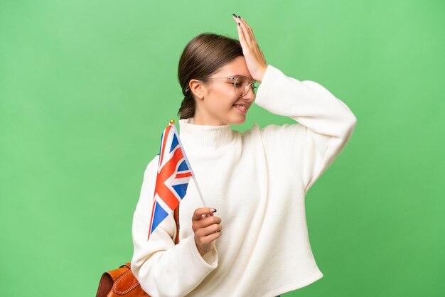 Menina caucasiana estudante adolescente segurando uma bandeira do Reino Unido sobre fundo isolado percebeu algo e pretendendo a solução