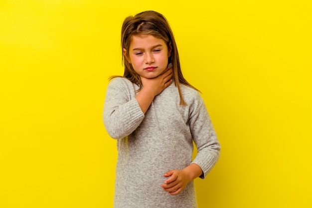 Menina caucasiana isolada em amarelo sofre de dor na garganta devido a um vírus ou infecção.