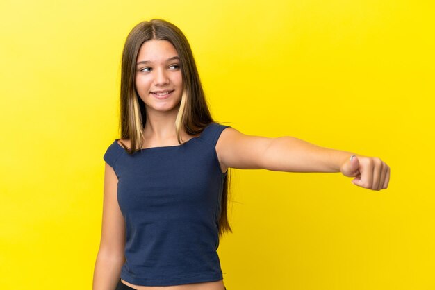 Menina caucasiana isolada em fundo amarelo dando um polegar para cima gesto