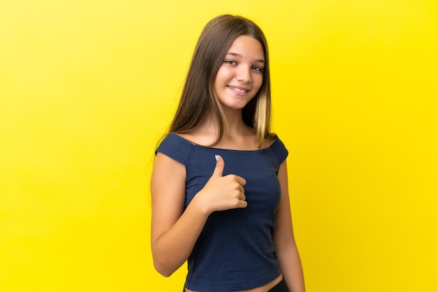 Menina caucasiana isolada em fundo amarelo dando um polegar para cima gesto