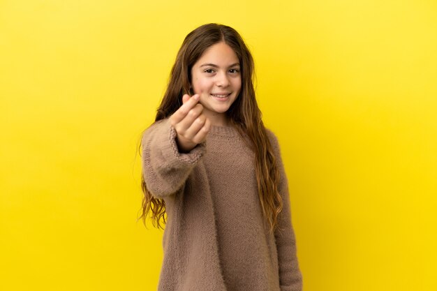 Menina caucasiana isolada em fundo amarelo fazendo gesto de dinheiro