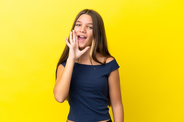 Menina caucasiana isolada em fundo amarelo gritando com a boca aberta