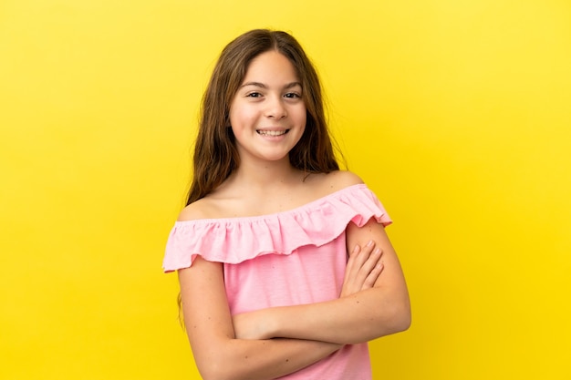 Menina caucasiana isolada em fundo amarelo, mantendo os braços cruzados na posição frontal