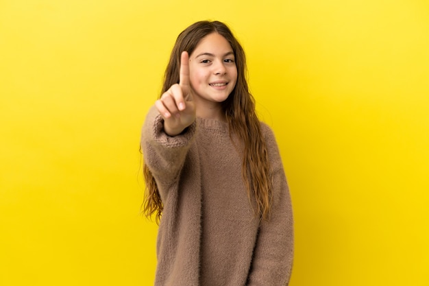 Menina caucasiana isolada em fundo amarelo, mostrando e levantando um dedo