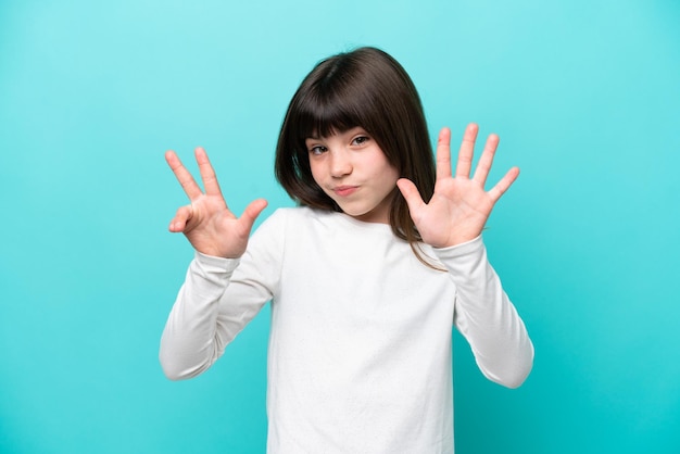 Menina caucasiana isolada em fundo azul contando oito com os dedos