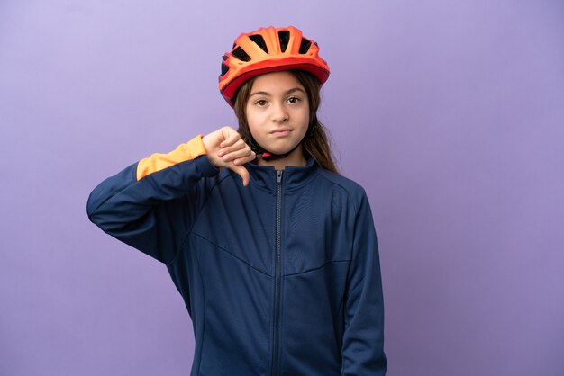 Menina caucasiana isolada em fundo roxo, mostrando o polegar para baixo com expressão negativa