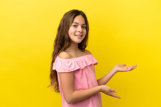 Foto menina caucasiana isolada em um fundo amarelo, estendendo as mãos para o lado para convidar para vir