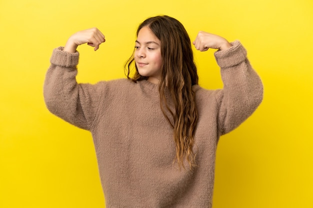 Menina caucasiana isolada em um fundo amarelo fazendo um gesto forte