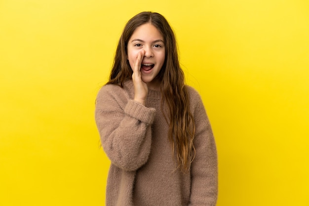 Menina caucasiana isolada em um fundo amarelo gritando com a boca bem aberta