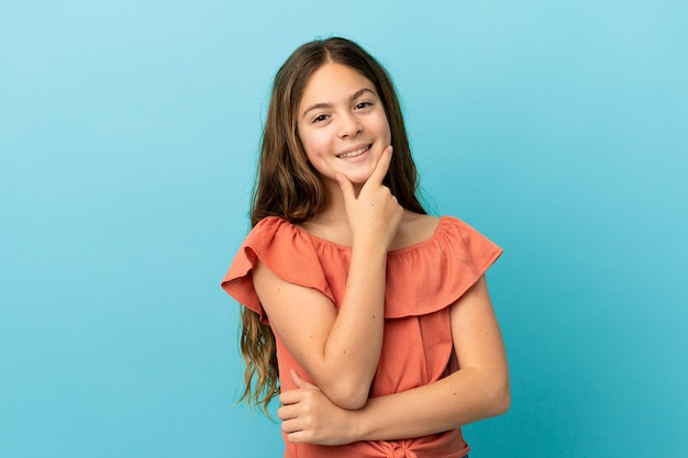 Menina caucasiana isolada em um fundo azul feliz e sorridente