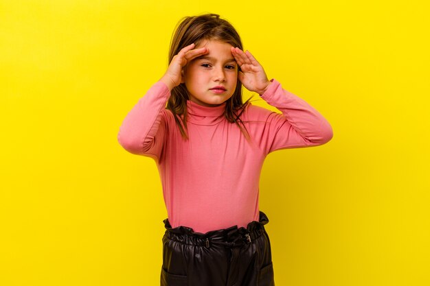 Menina caucasiana isolada na parede amarela cobrindo as orelhas com os dedos, estressada e desesperada por um ambiente barulhento.