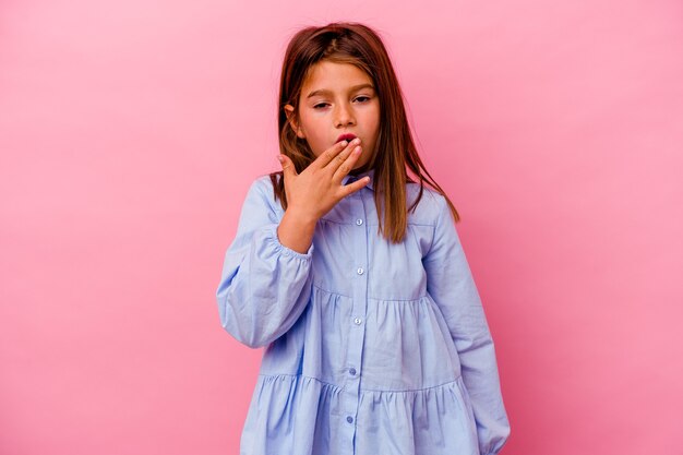 Menina caucasiana isolada no fundo rosa bocejando mostrando um gesto cansado, cobrindo a boca com a mão.